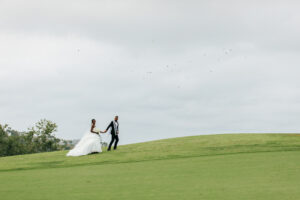 bride and groom holding hands walking on golf course